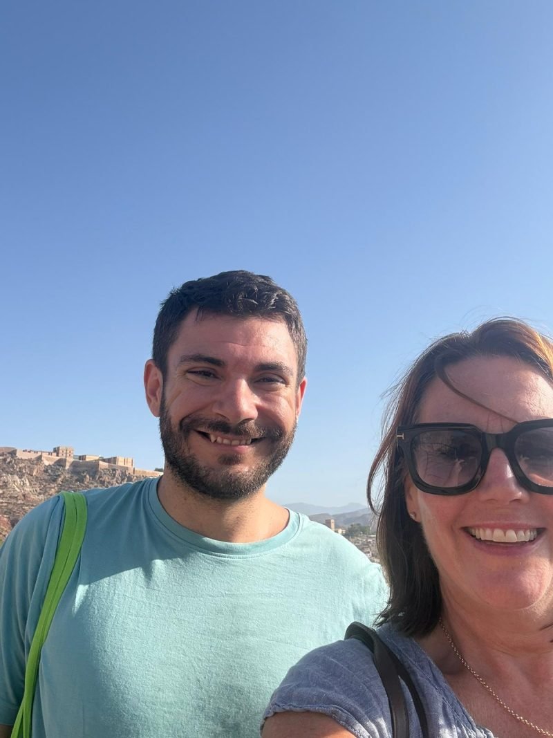 Selfie of Héctor with a student, a hilltop castle behind
