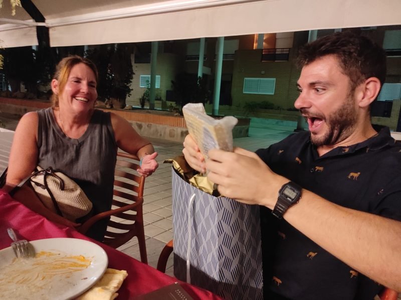 Héctor and a student at dinner, opening a gift
